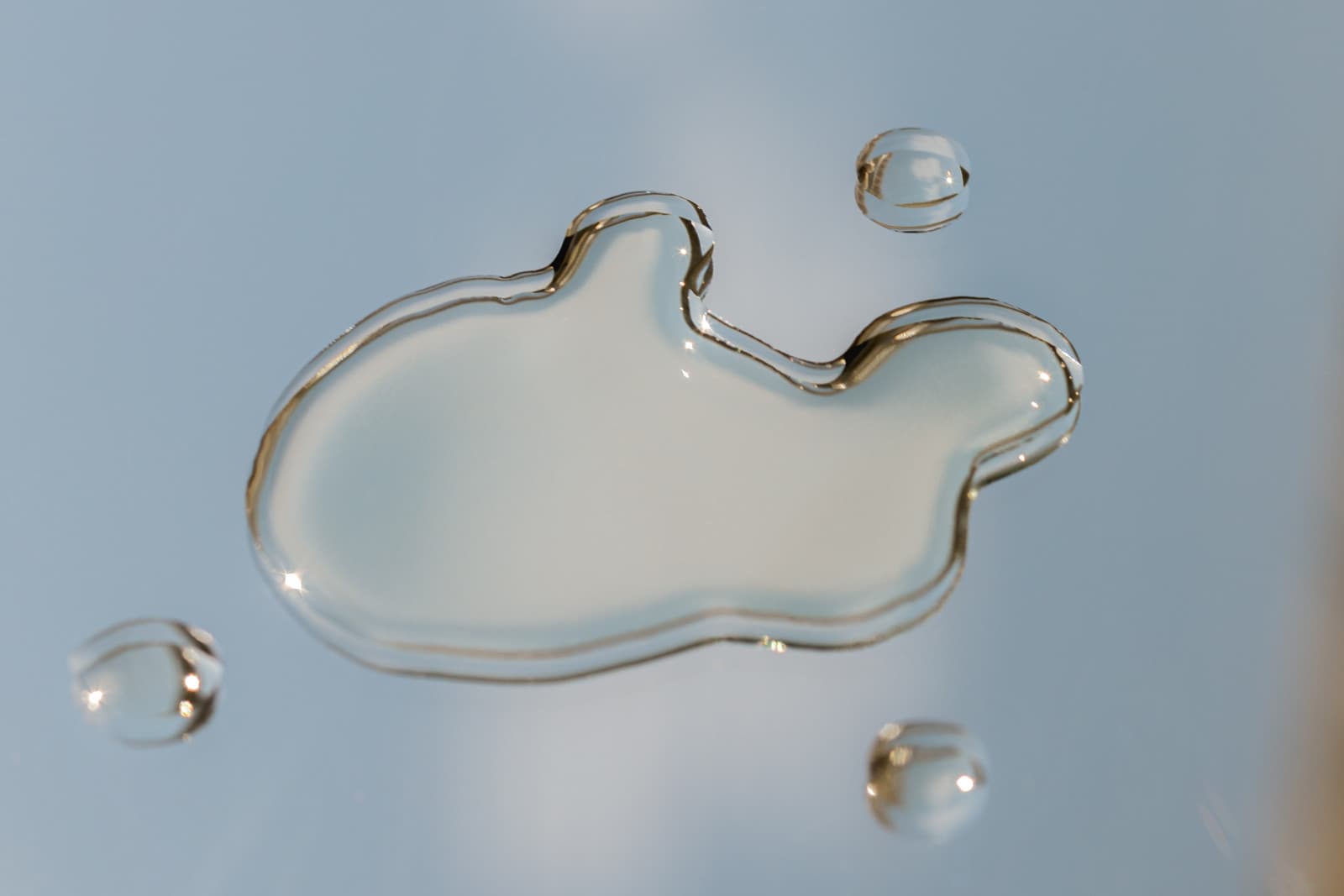 A drop of clear serum resting on a light blue surface