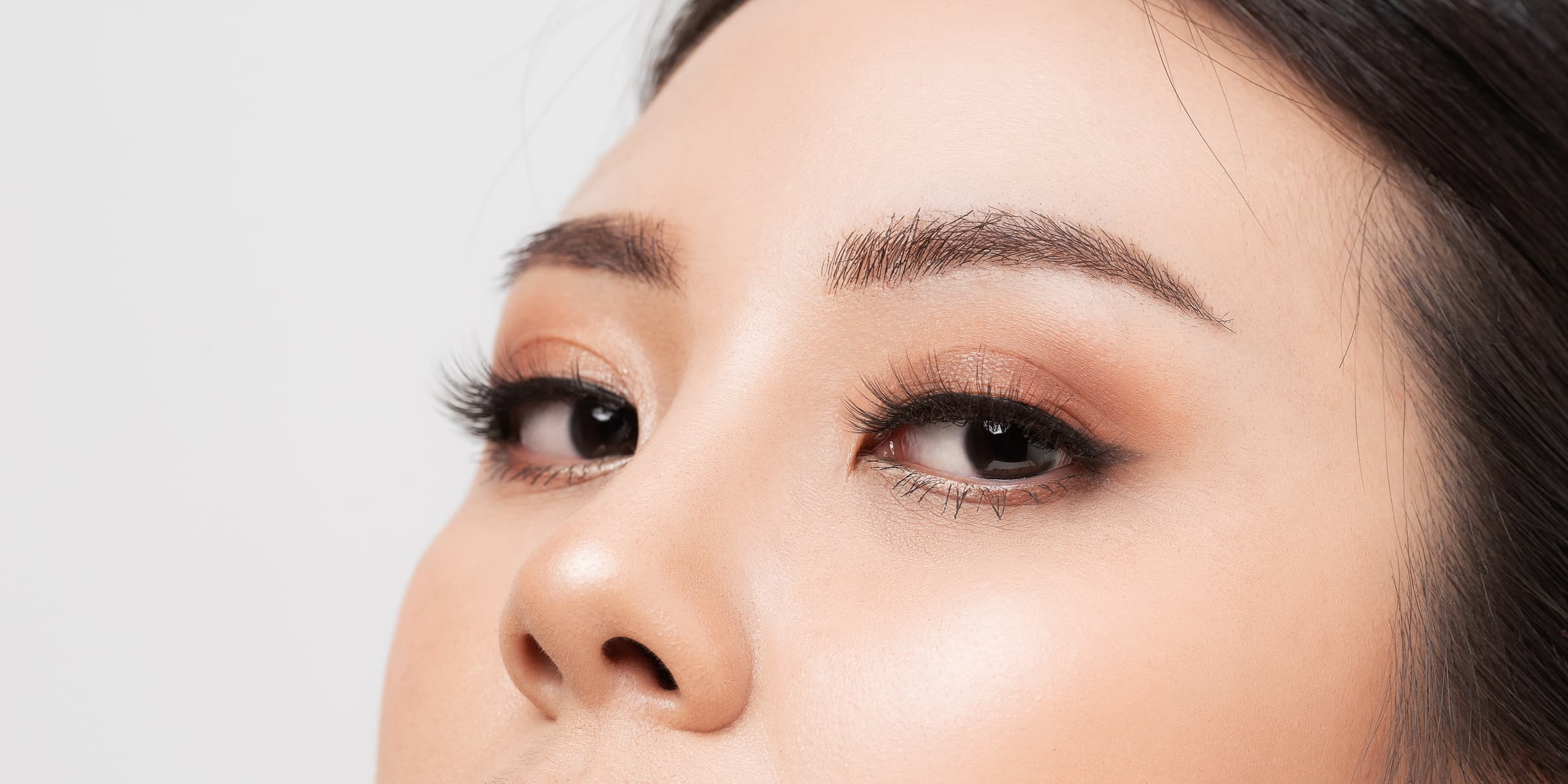 A close-up of a woman's brow area. Her lashes are long and her eyebrows are expertly manicured.