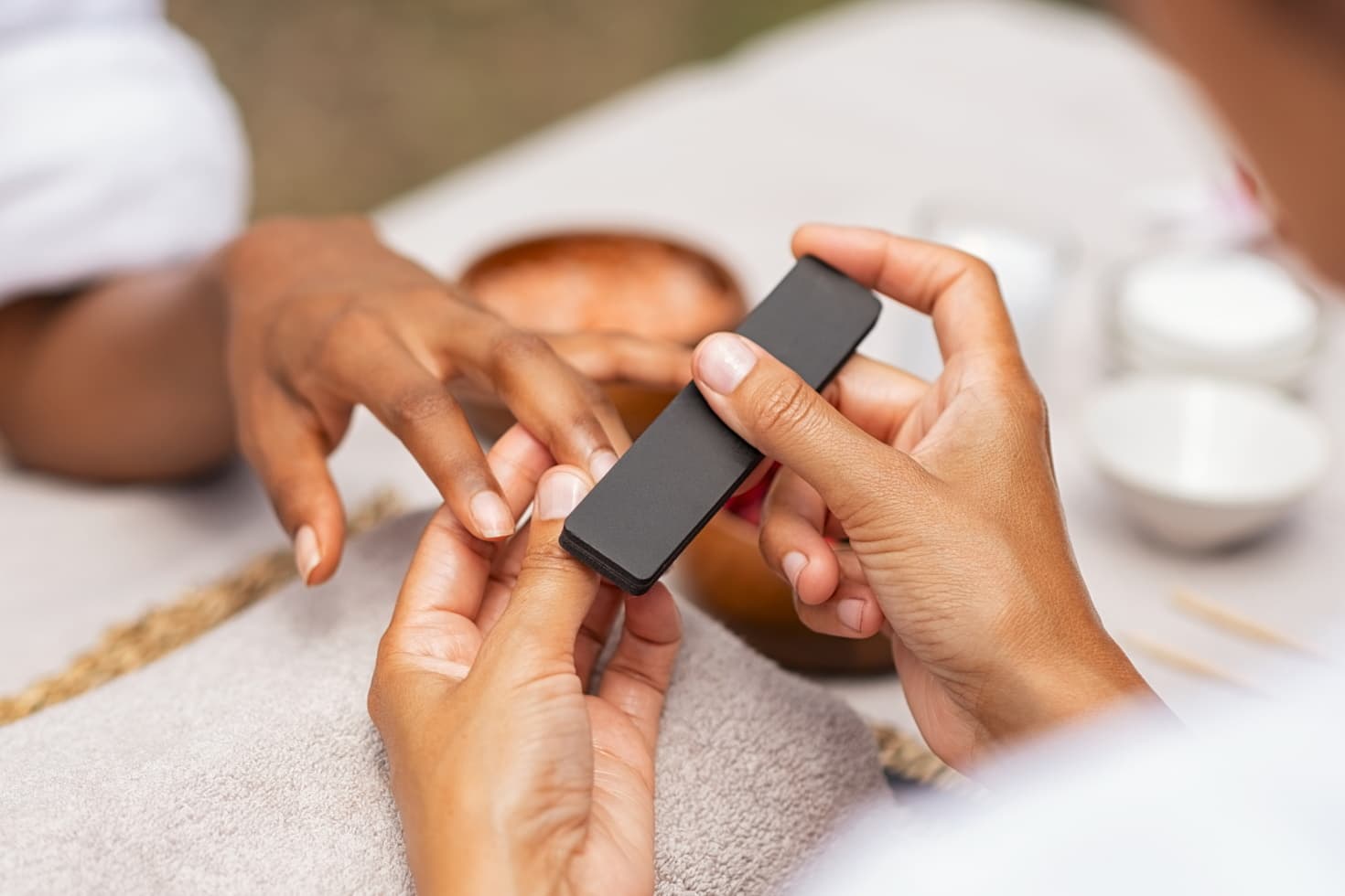 Technician files woman's fingernails during a deluxe manicure.