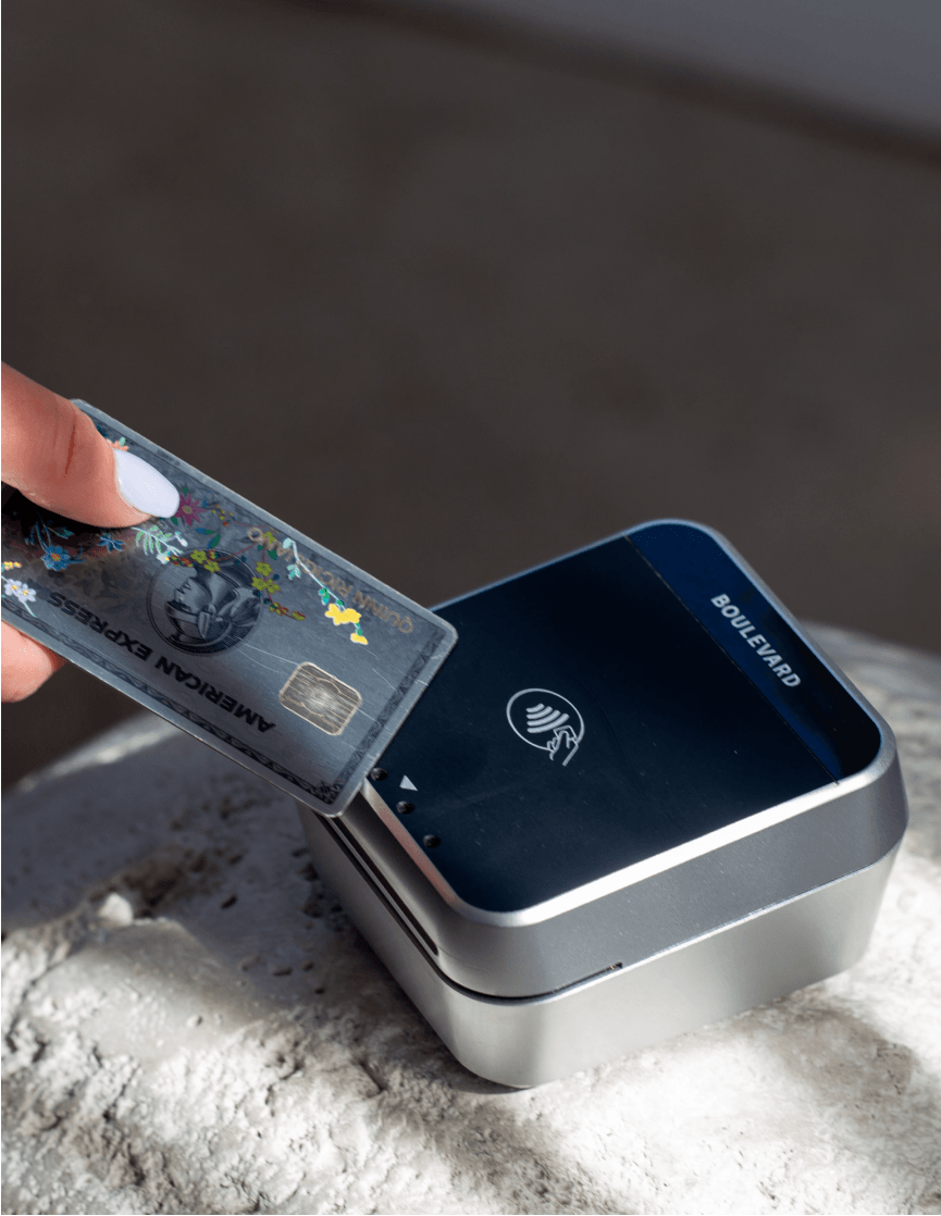A client tapping a card on a Boulevard card reader at checkout