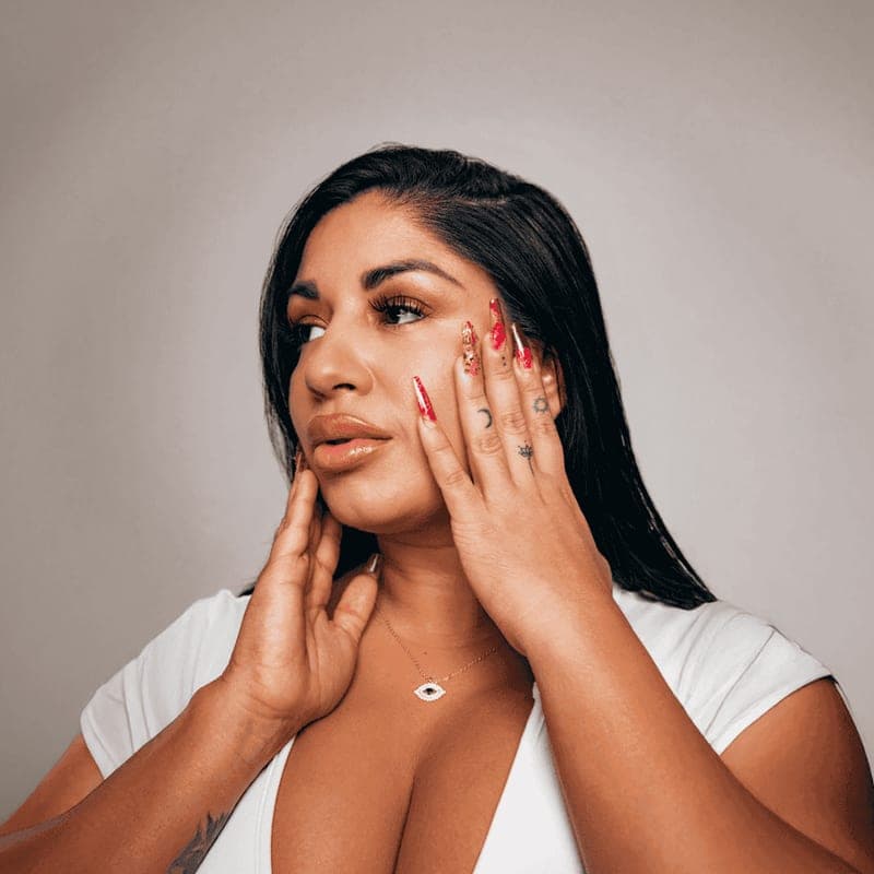 A woman with long red nails resting her hands against her face