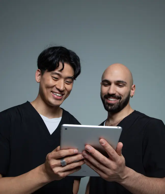 Two smiling team members reviewing a tablet together.