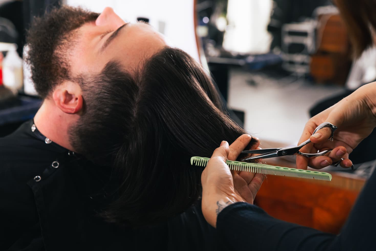 A barbershop client leans back as the barber cuts his hair.