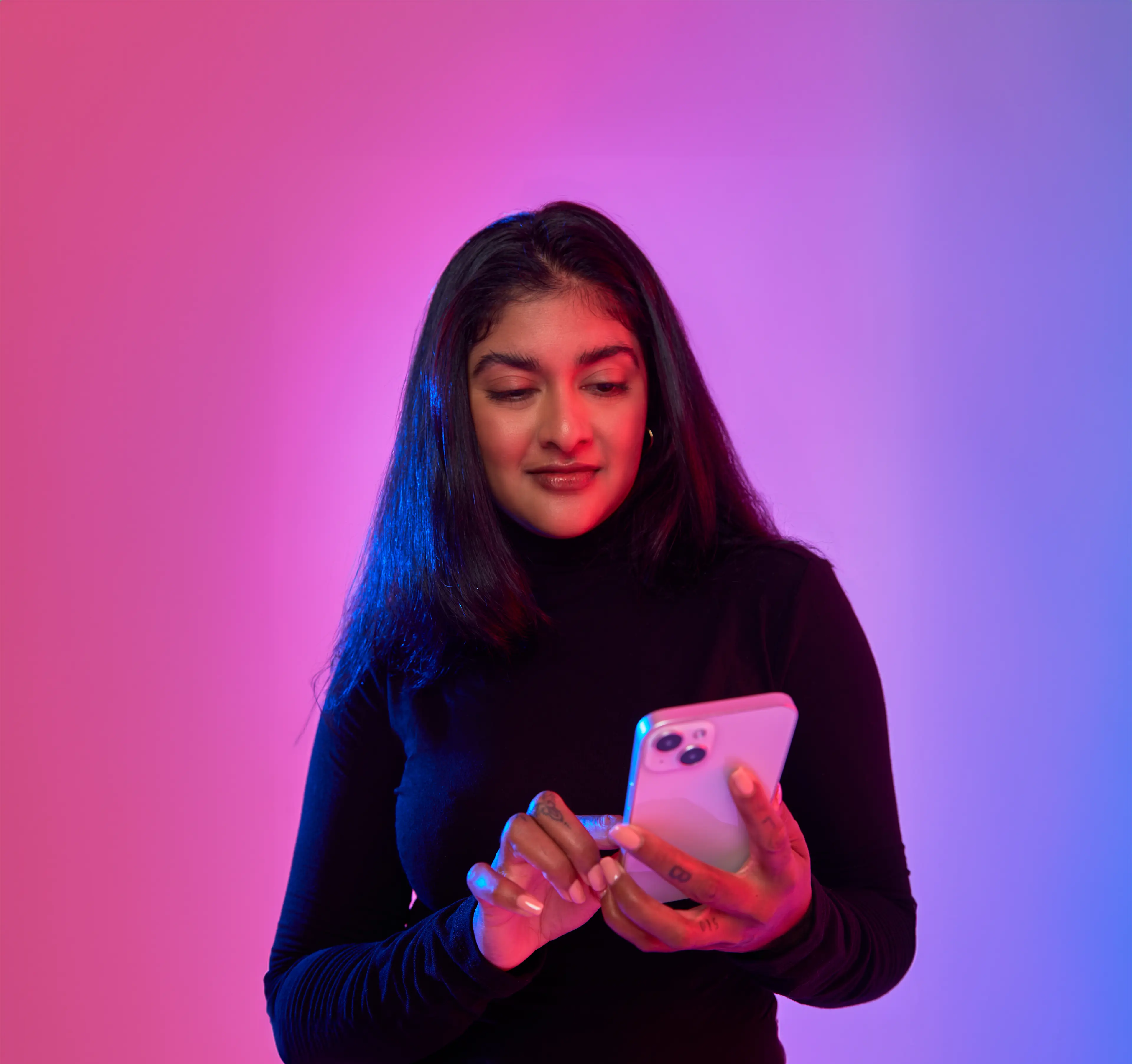 Woman standing as she scrolls through her phone.