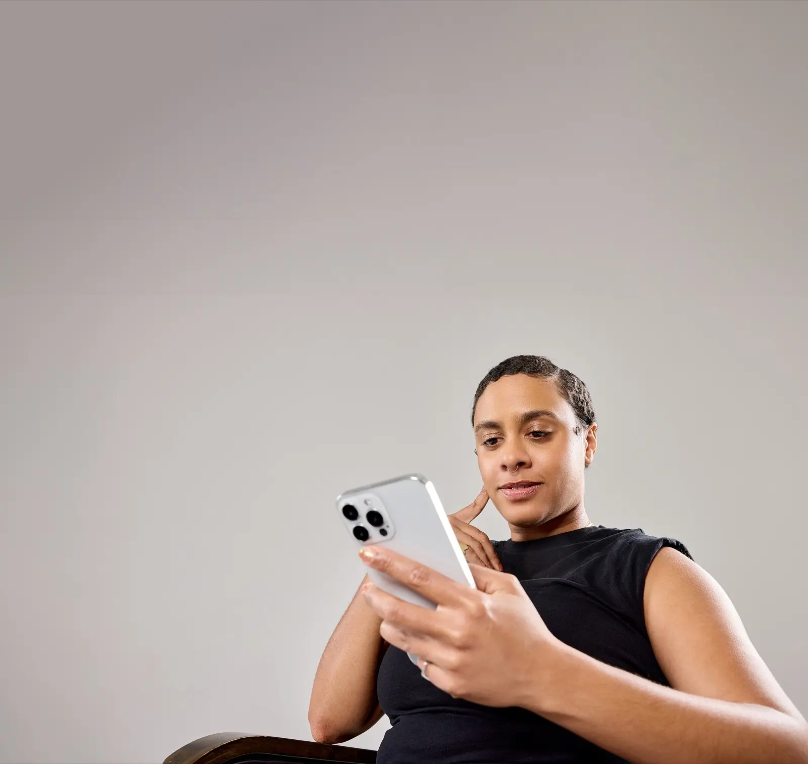 A client sits in a salon chair looking at her phone, reviewing her Buy Now, Pay Later payment options.