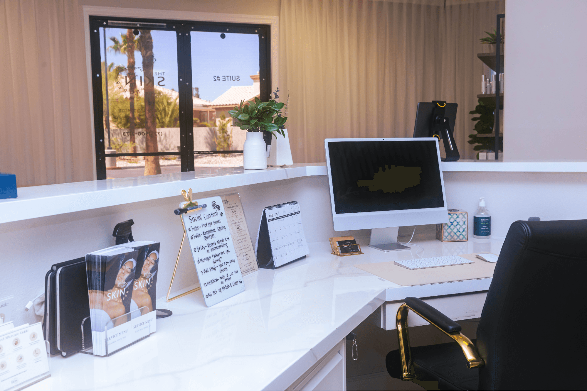 A computer monitor sits on a desk near a keyboard, a mouse, a calendar, a clipboard, and a brochure holder.