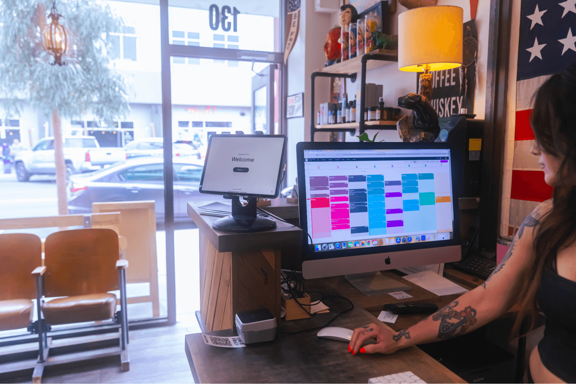 A woman in a hair salon looks at a scheduling app on a computer screen.