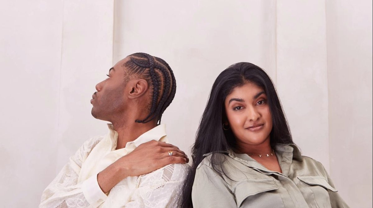 wo people sitting in chairs next to each other, with one person looking directly at the camera and the other looking away