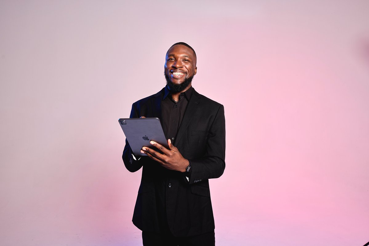 A medspa manager holds a tablet, smiling as he welcomes medspa clients.