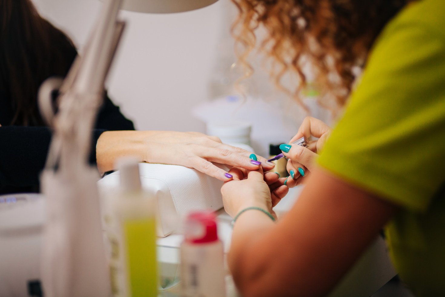 A nail tech gives a client a colorful manicure.
