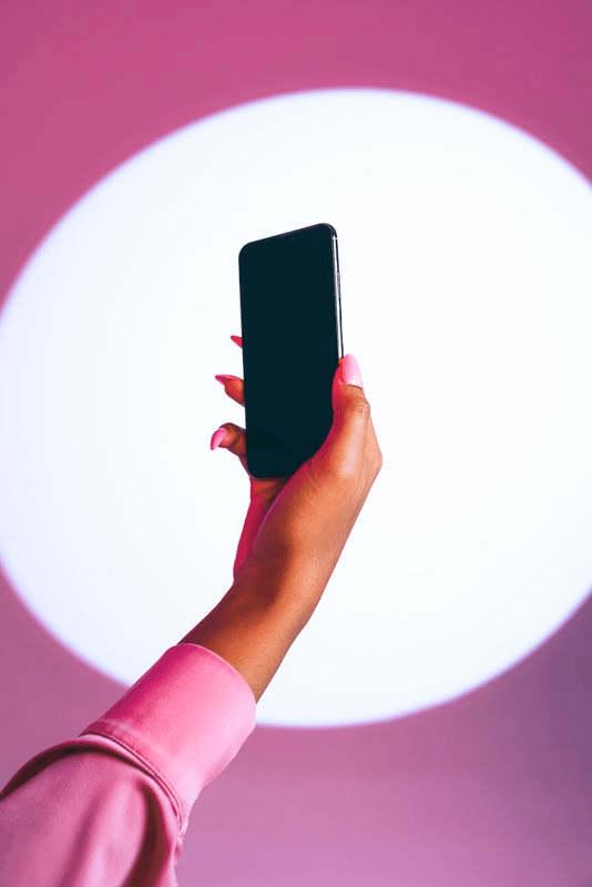 A hand with perfectly manicured nails holds up a smartphone.