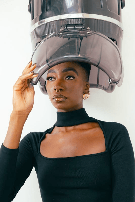 A woman sits under the dryer at a salon.