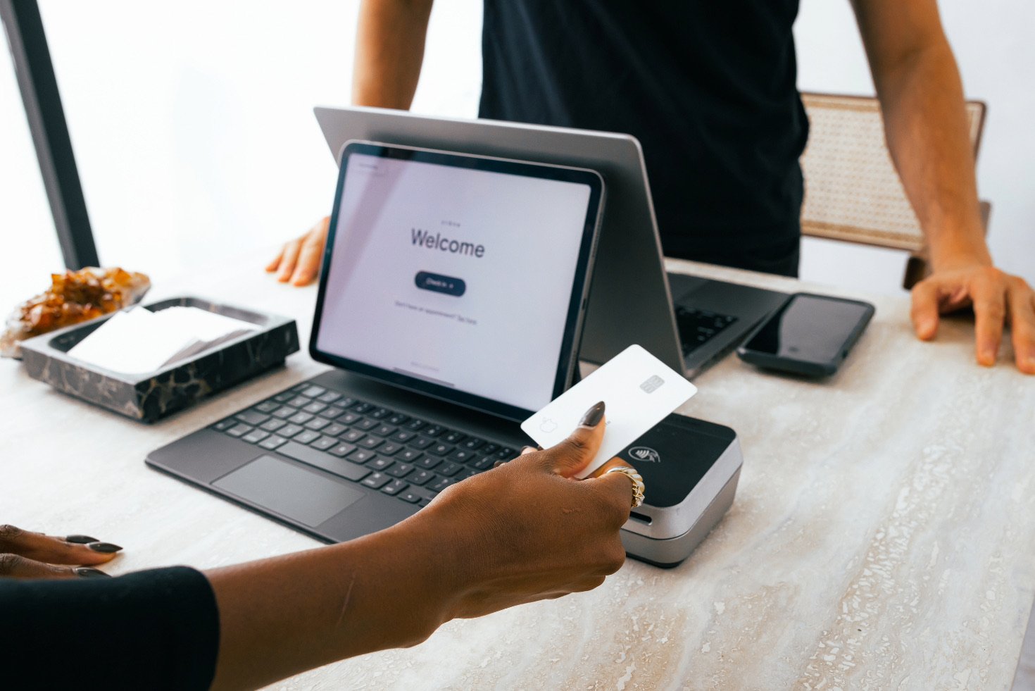 A client holds their credit card over a contactless payment reader at the front desk of a spa.