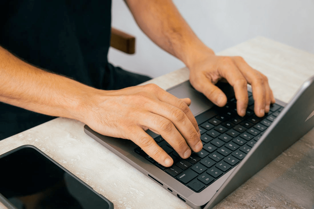 A pair of hands typing on a laptop.