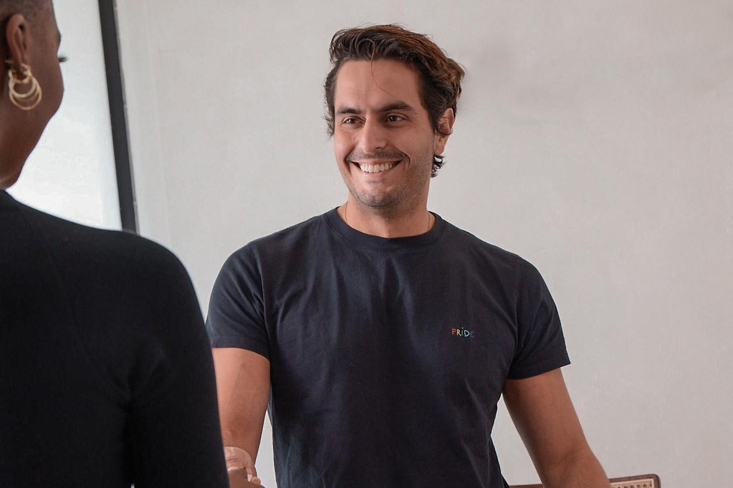 A salon stylist smiles as he greets a client.