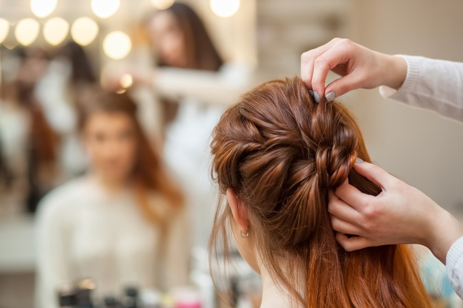 Hairstylist braiding client's hair.