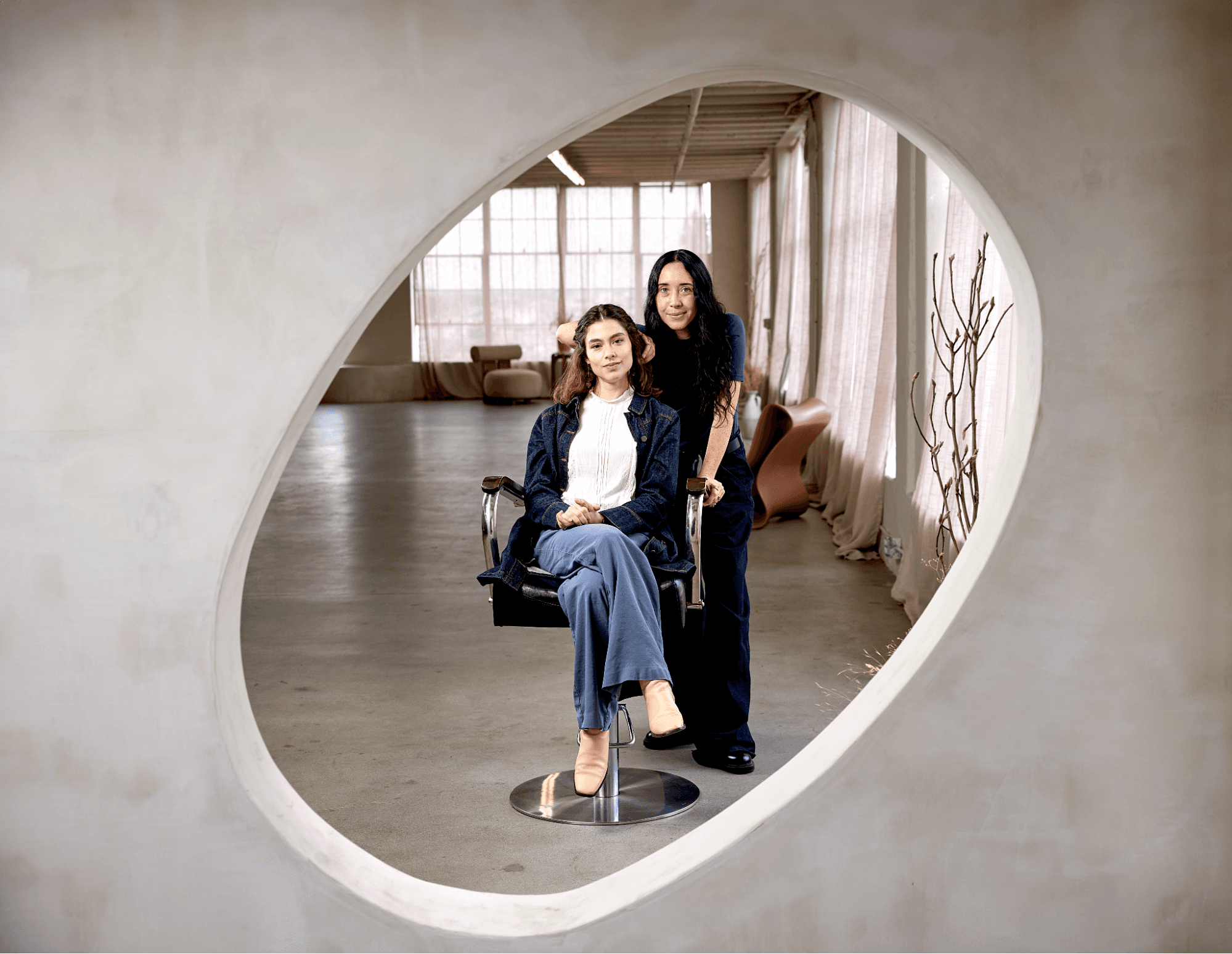 A hair stylist services a customer in her chair while looking into a mirror.