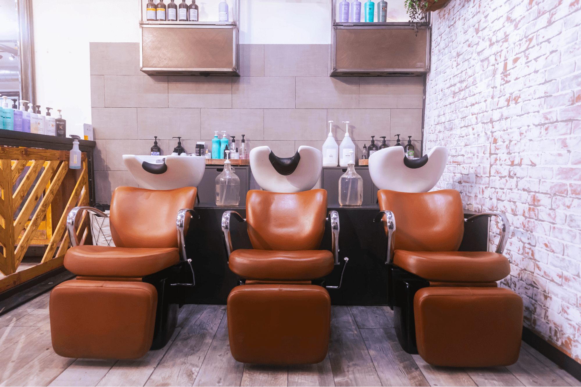 Three shampoo chairs sit near the wall of a hair salon.