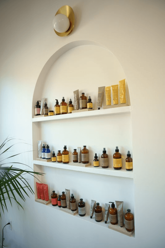 Haircare and skincare products line shelves in a white salon wall.