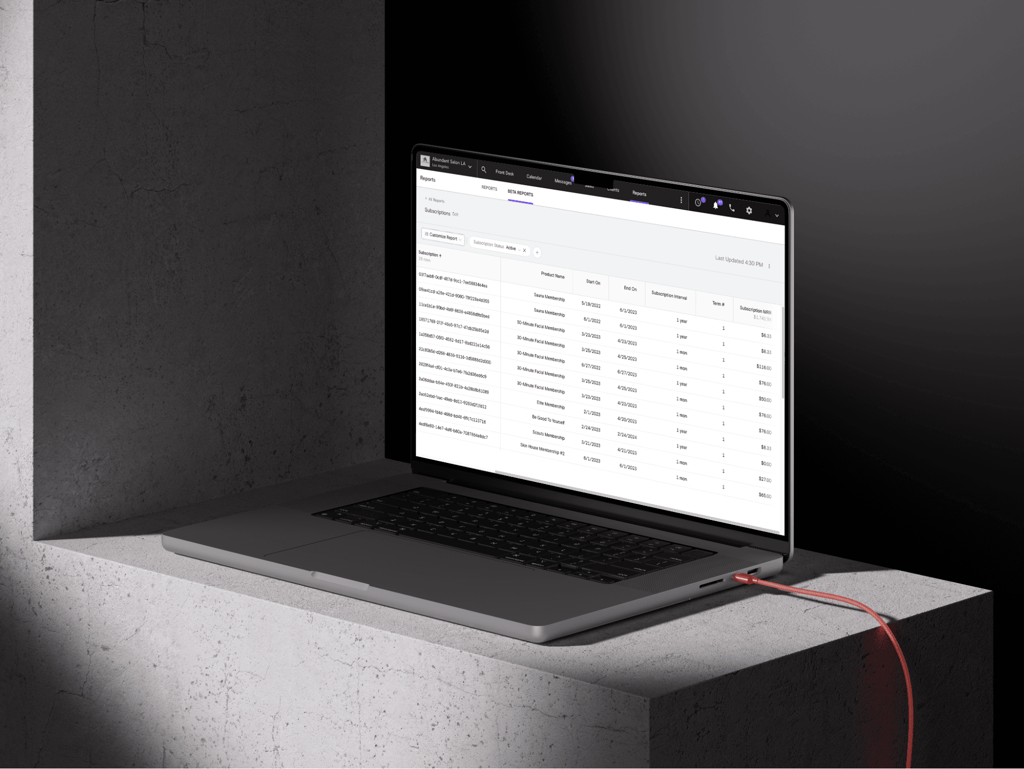 An open laptop sits on a slate table. The screen shows Boulevard's Reporting tools.