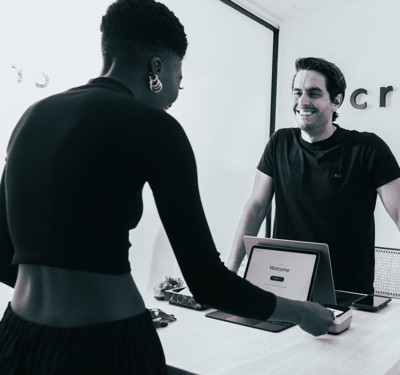 A satisfied customer uses a tablet at a reception desk to complete a transaction.
