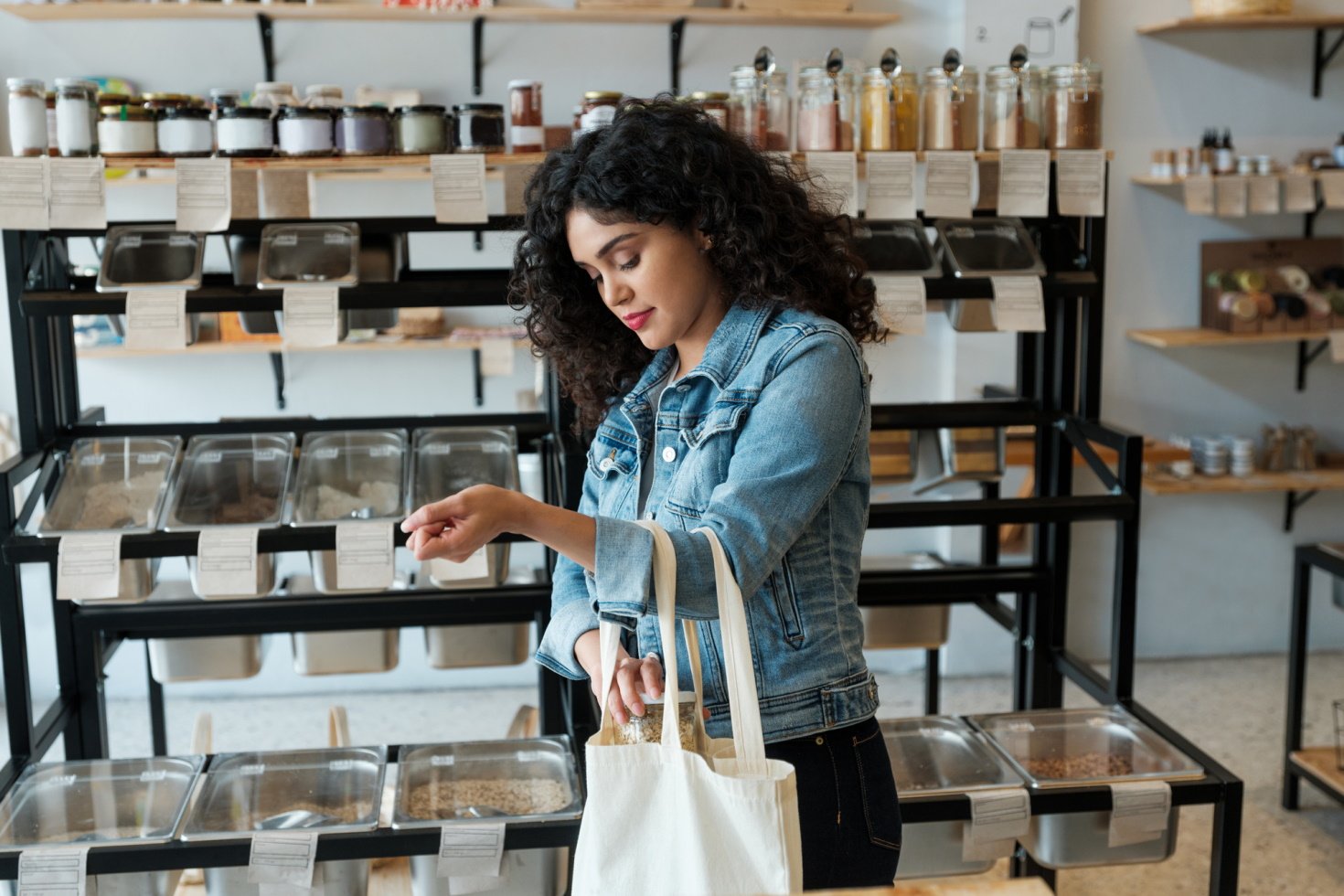 A young woman using a reusable shopping bag in a zero waste store.